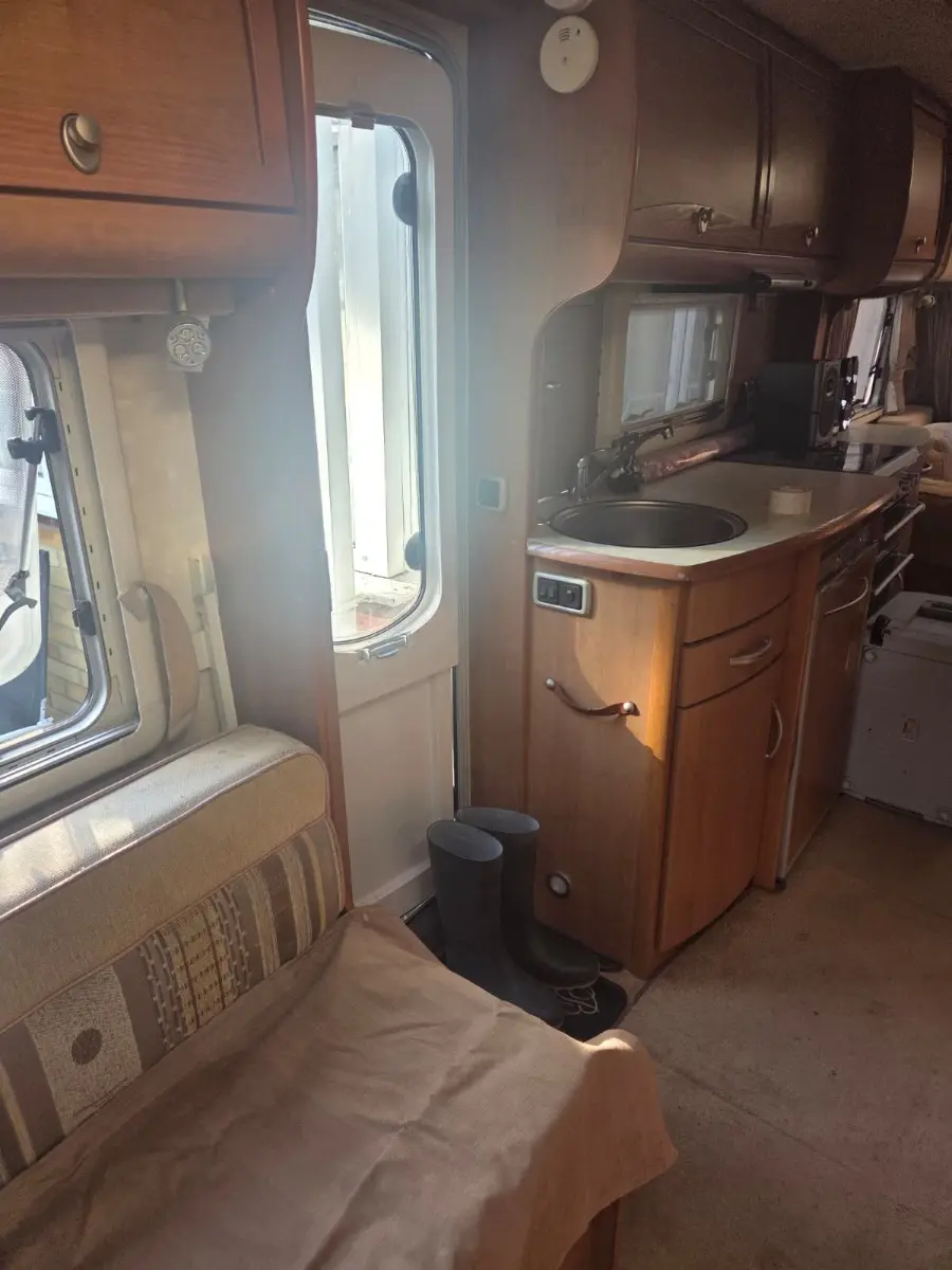 Dated timber kitchen units, sink and hob inside a tourer with the upholstery still in place, the kind of interior detail a photo quote is read from