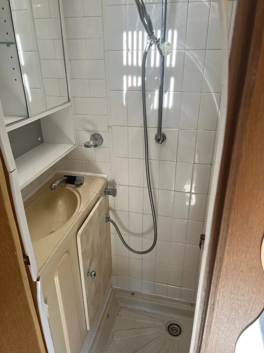 Tired tiled shower room inside an older touring caravan, the sort of damp and interior damage that sets the Basingstoke price