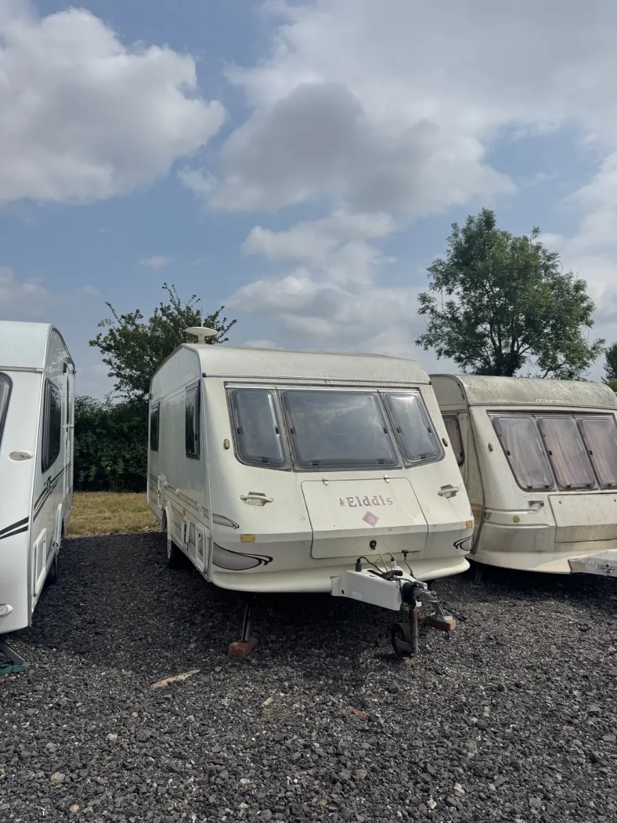 A row of touring caravans parked nose to tail on a gravel storage area, the kind of site collections get booked from across the Royal Borough
