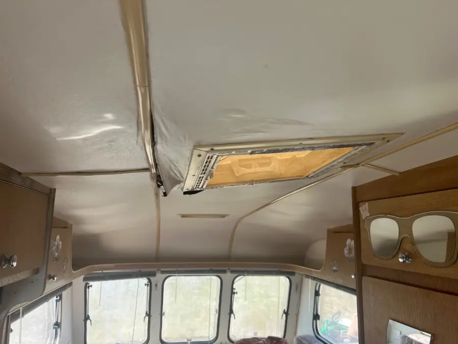 Water-stained caravan ceiling panel delaminating around the rooflight surround, the damp damage that moves a job out of the towable price band