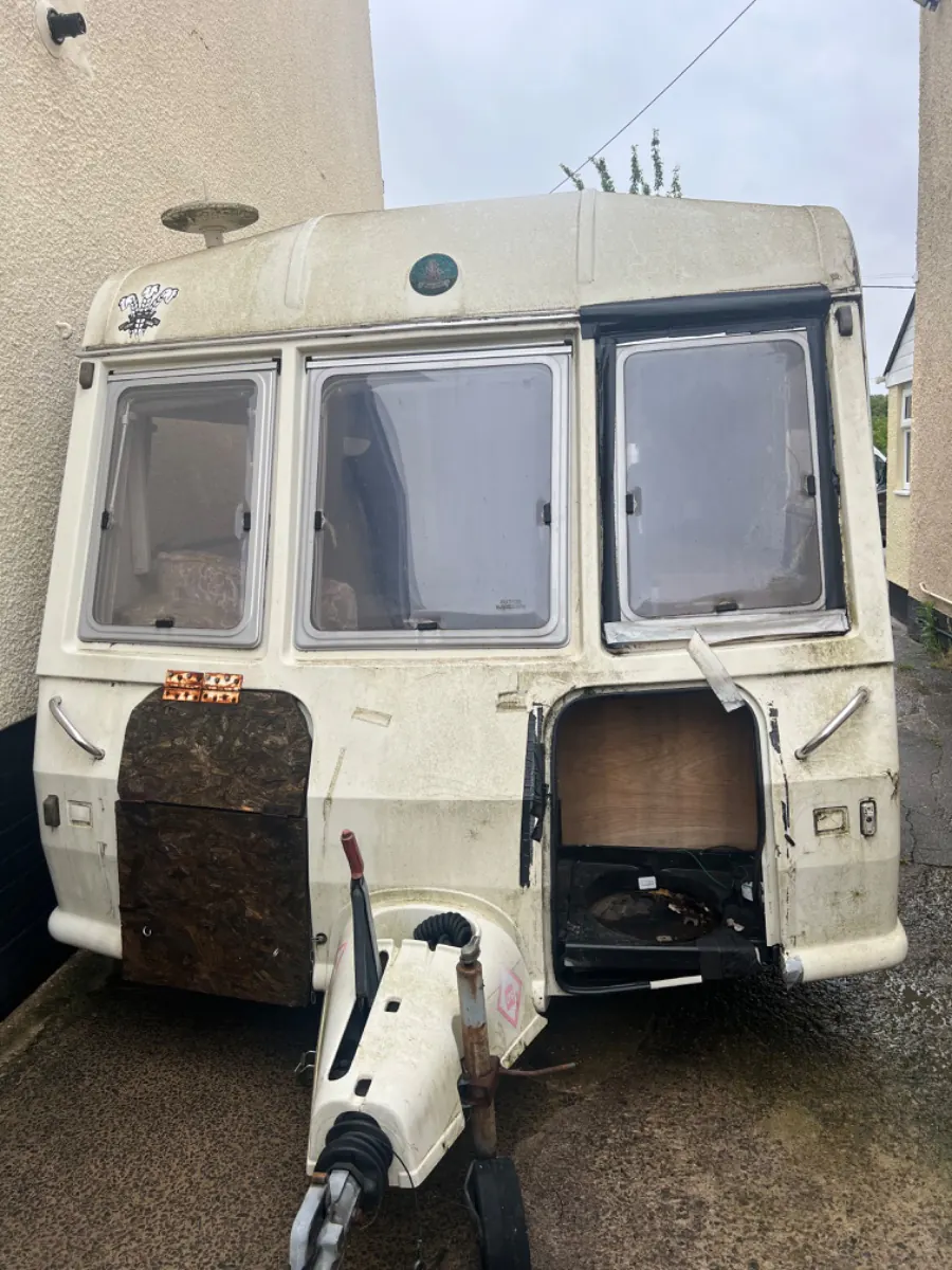 Touring caravan with a wheel off and the hub left exposed, the front panel split and the stabiliser hanging loose, condition and access are what move a removal price