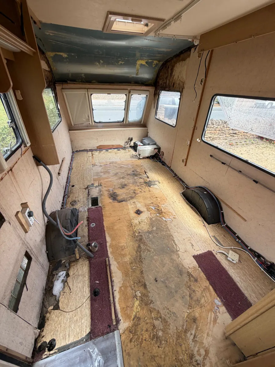 Inside a caravan stripped back to the bare floor with the fittings lifted out and wiring left loose, part-way through being broken up