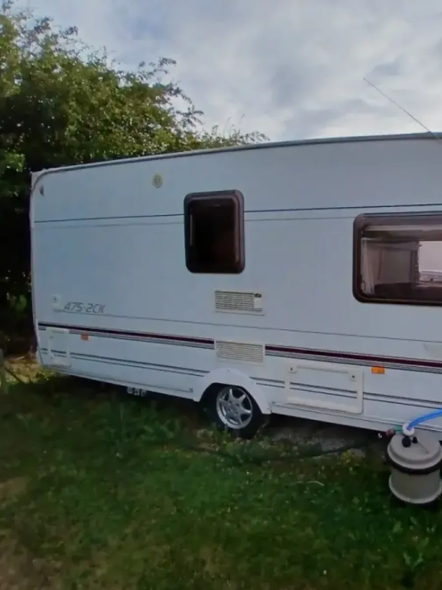 White Clubman touring caravan standing on grass with a gas bottle alongside, kept at home rather than on a storage site