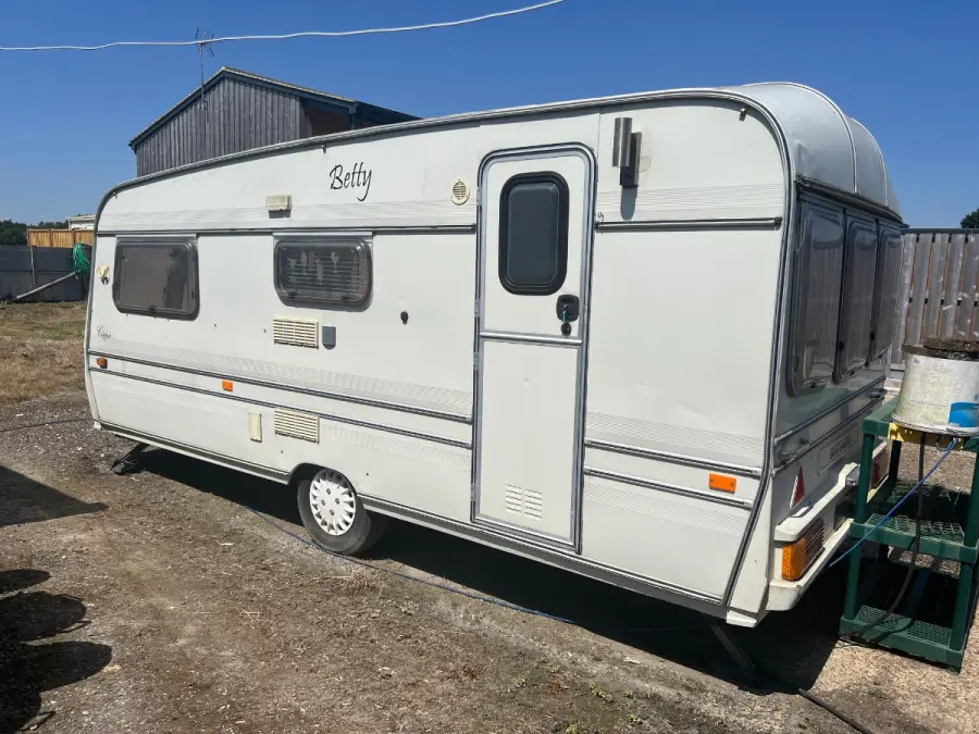 Full side view of a white touring caravan on hardstanding, wheels and hitch intact, showing the height that will not clear a 170 cm barrier