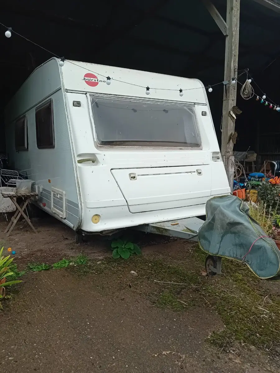 Touring caravan parked under cover in a barn, complete and out of use, the situation many owners are in before they decide to sell