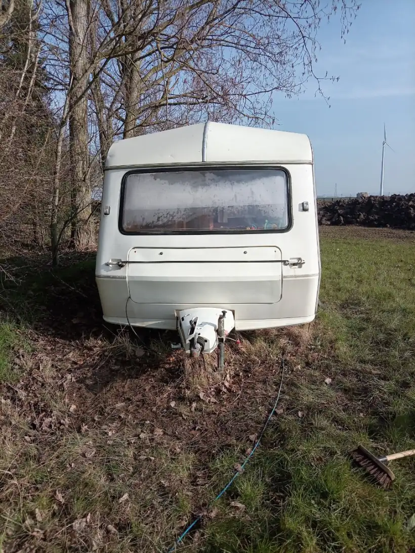 Touring caravan on soft, churned ground under bare trees with its nose dropped on the jockey wheel, the sort of access that decides how a collection is planned