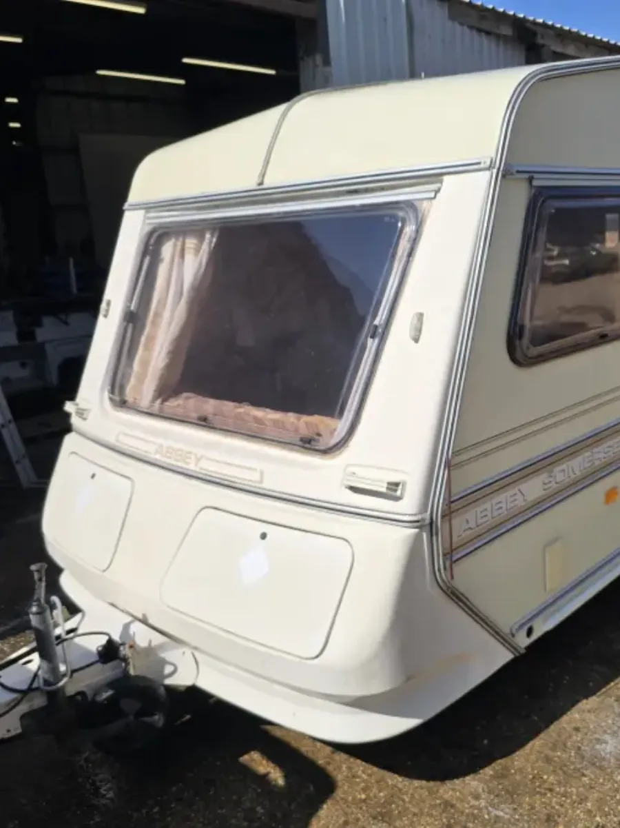 Cream Abbey Somerset touring caravan, hitched and complete, standing on hardstanding outside a workshop