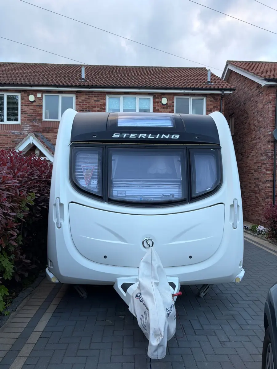 Clean modern touring caravan on a block-paved drive with its hitch cover fitted, the stronger end of the tourers we are asked to buy