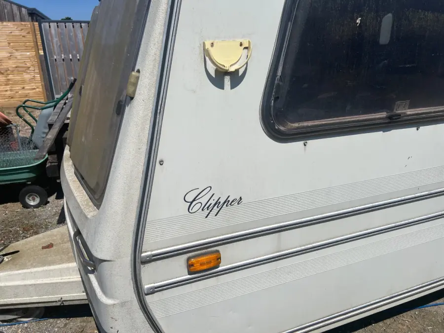 Close view of a weathered touring caravan flank with its model badge and side marker, the sort of detail worth photographing when requesting a quote