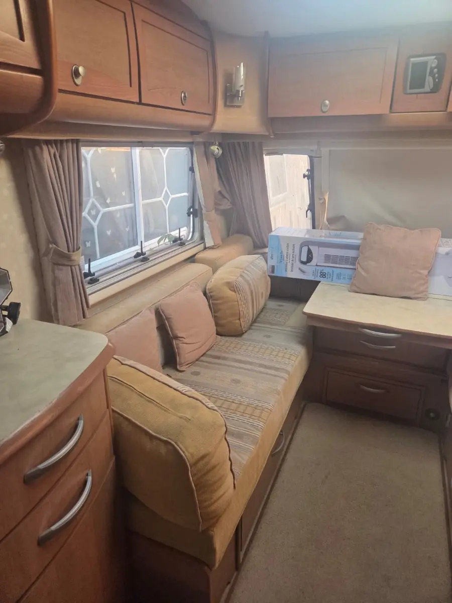 Caravan interior with overhead lockers, cushioned bench seating and fitted worktops, the fixtures separated out for reuse before the shell is broken down